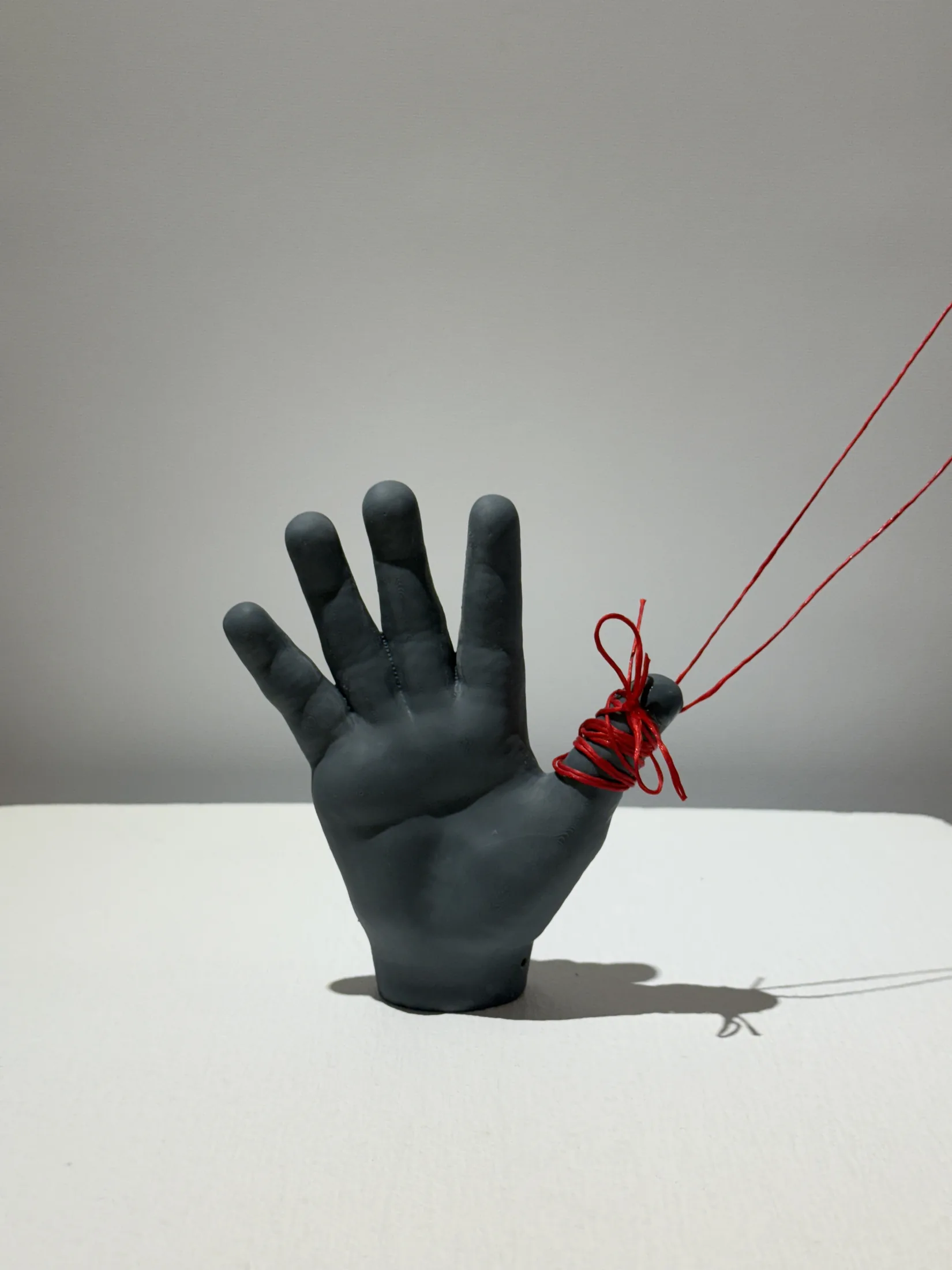Hand sculpture with red thread from Pixels to Pieces.
