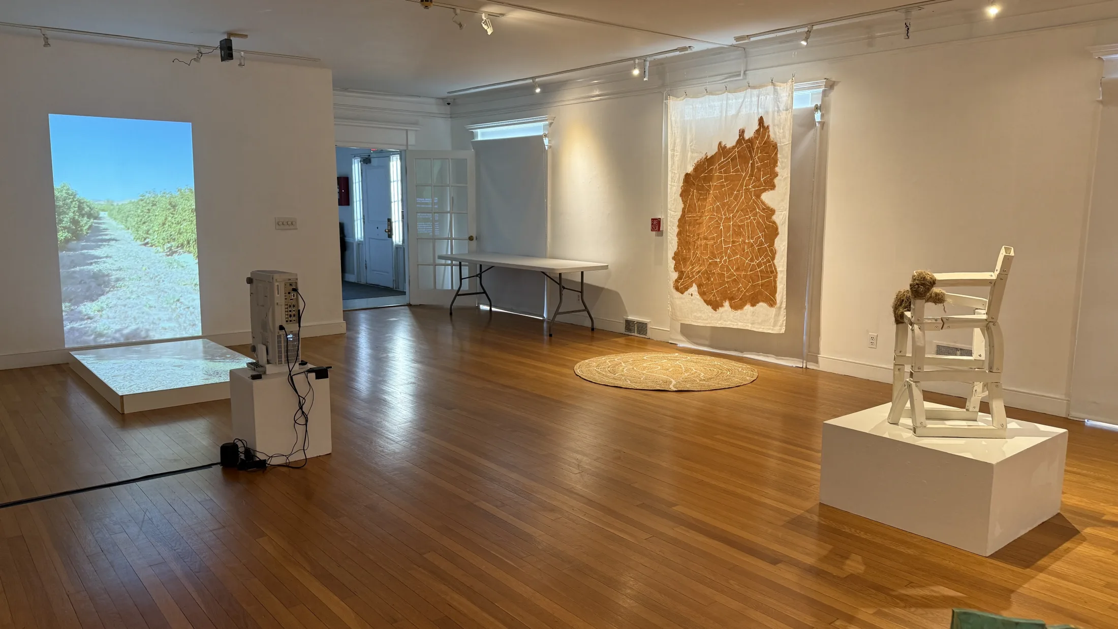 Gallery view of Displacement Weaves with projection, textile work, and floor-based installation.