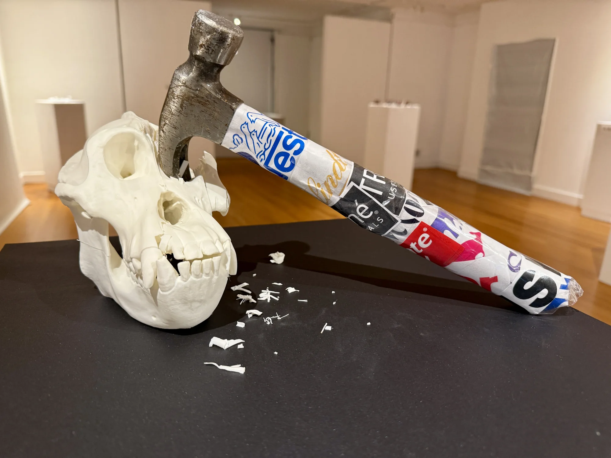 A white skull form beside a hammer with a handle covered in printed graphics.