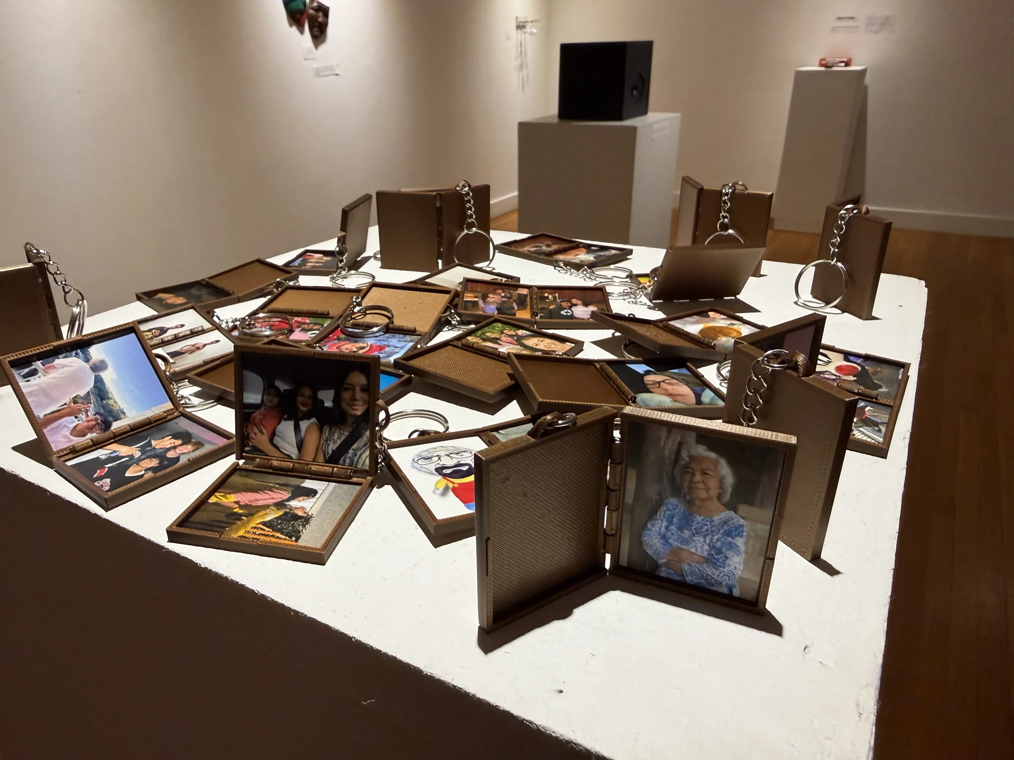 An arrangement of picture frames and photographs spread across a gallery plinth.