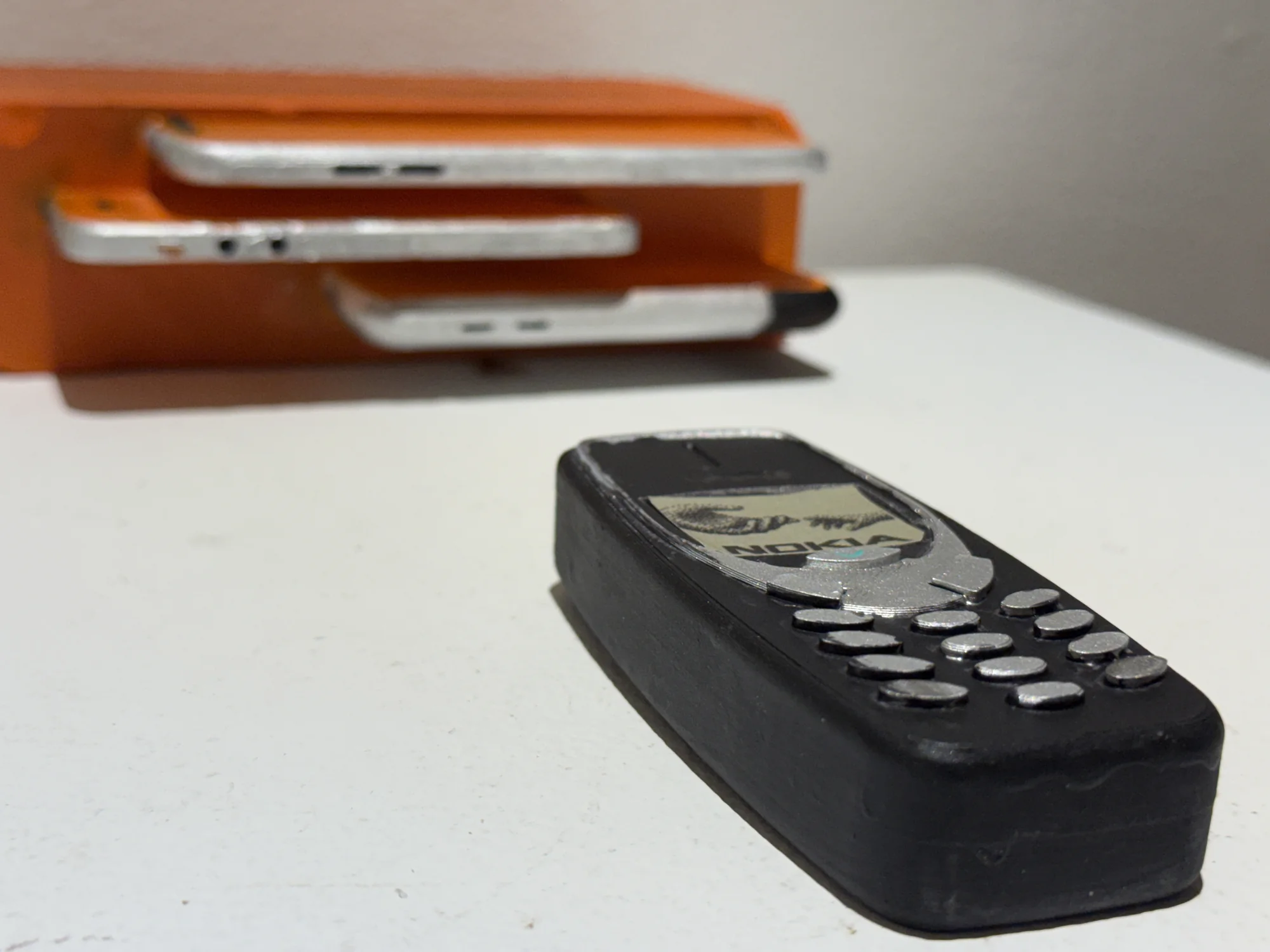 A black mobile phone form displayed in front of stacked orange trays.