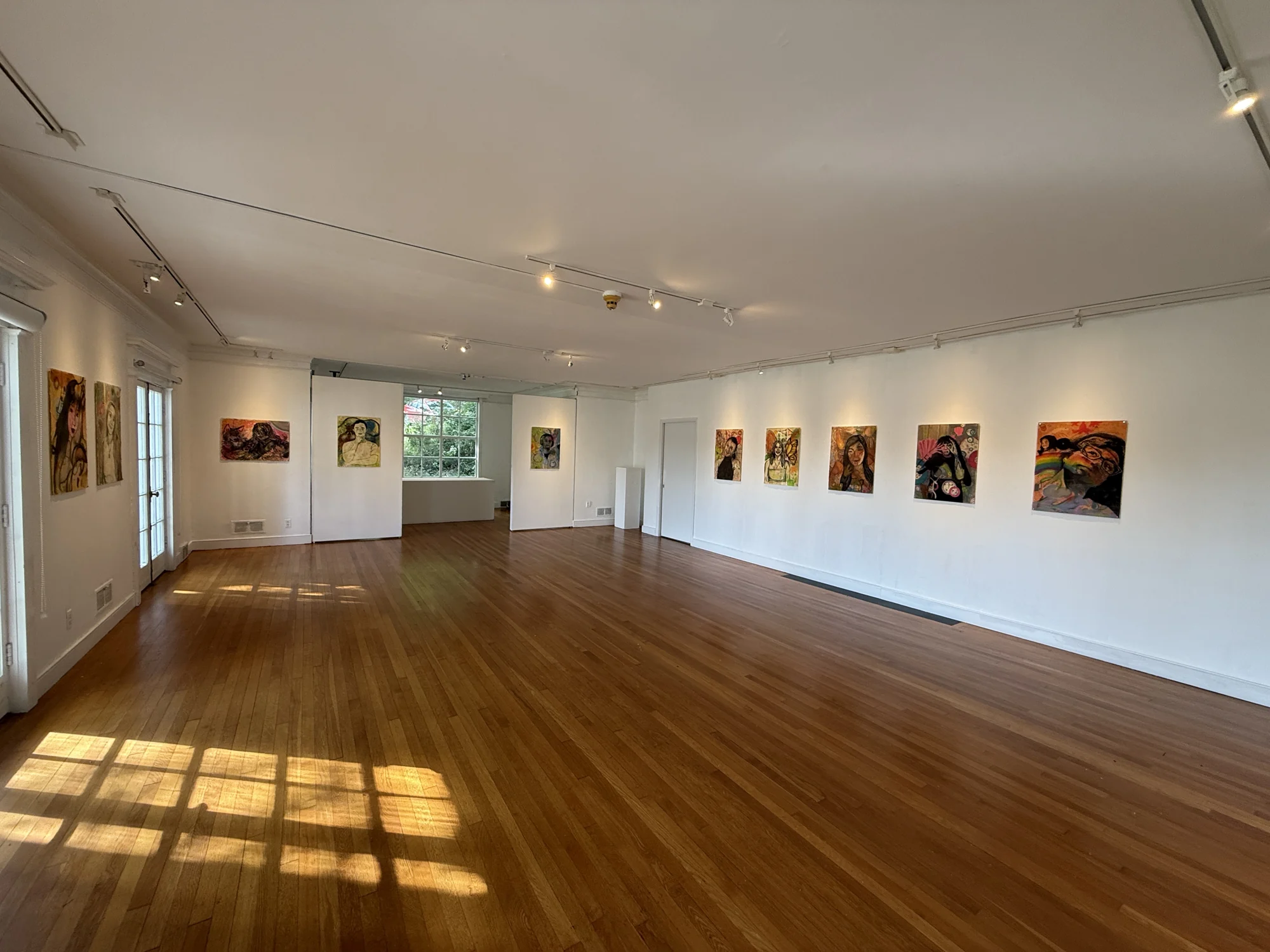 Wide view of the gallery with self-portrait drawings displayed along the walls.