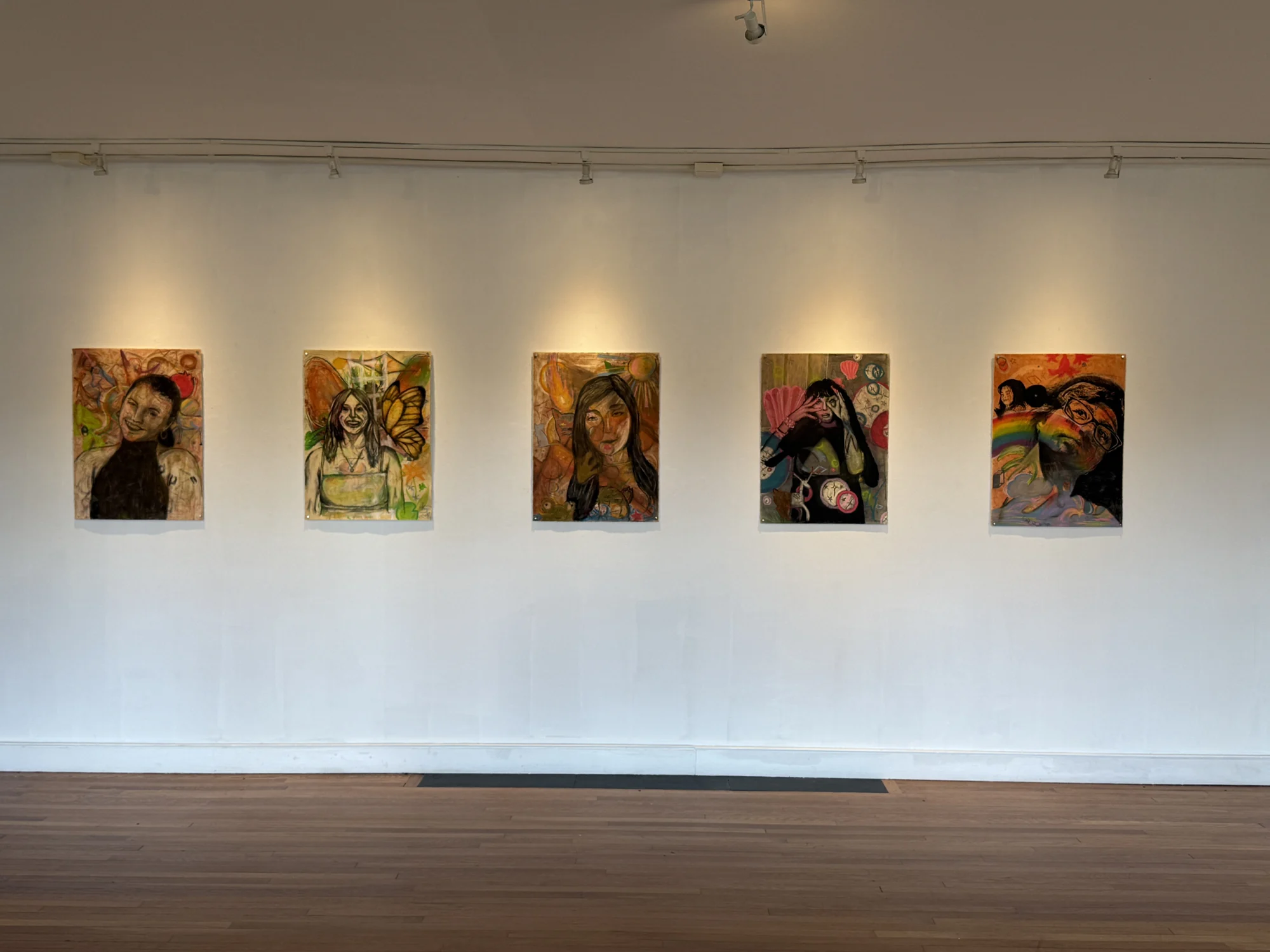 Five self-portrait drawings arranged across a white gallery wall.