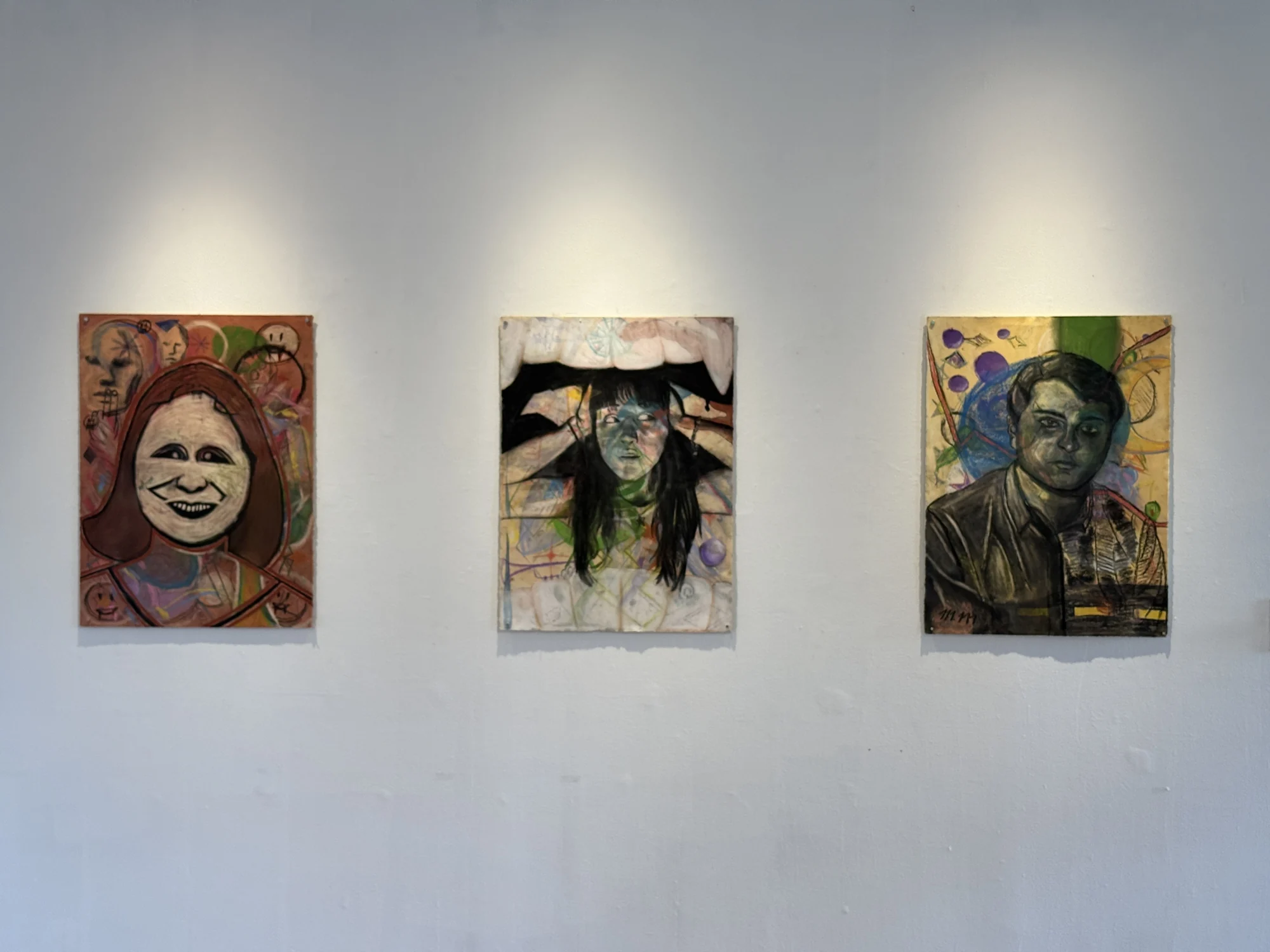 Three self-portrait drawings combining faces with symbolic imagery.