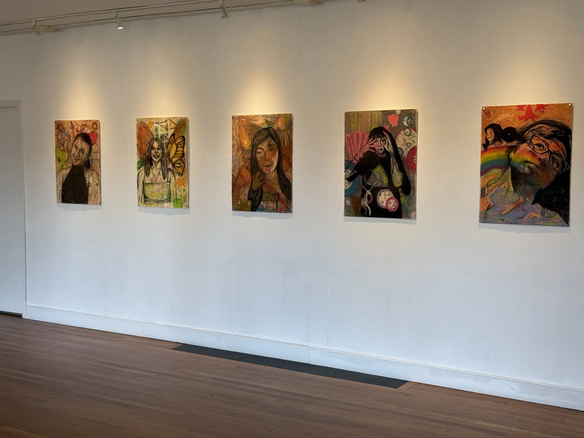 Angled installation view of five self-portrait drawings.